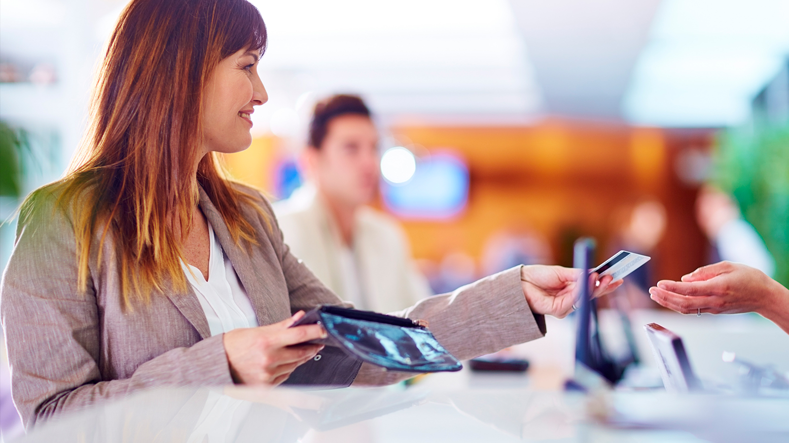 Woman offering Visa card at counter.