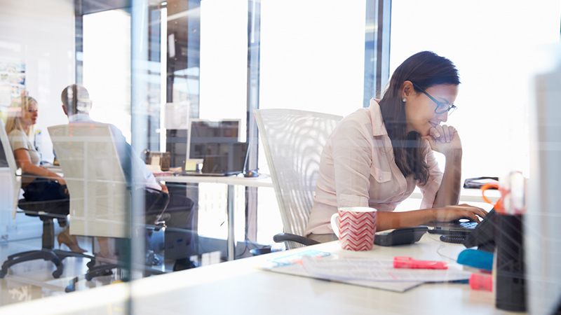Woman in office working on computer.