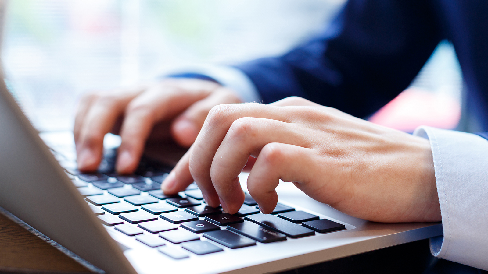 Close up of hands typing at a laptop keyboard.