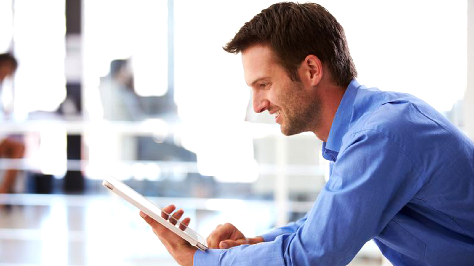 Man smiling at a tablet. 