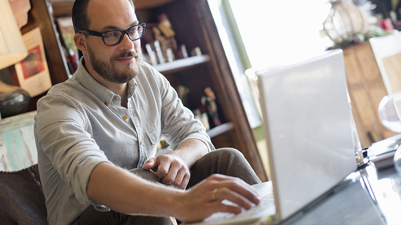 A man sitting while using a laptop.