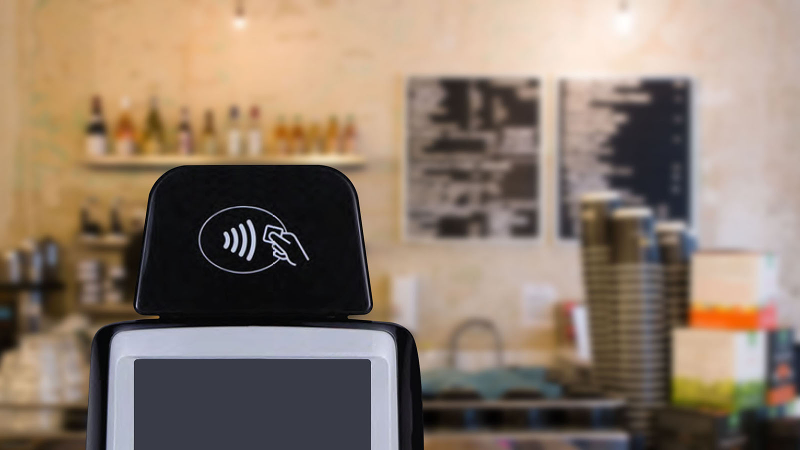 NFC terminal displaying contactless logo in a coffee shop.