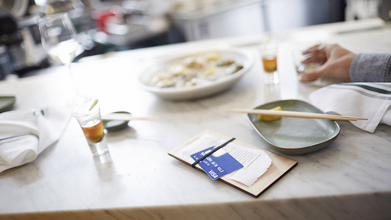 Restaurant table with half empty dishes and a bill with a Visa credit card on top.