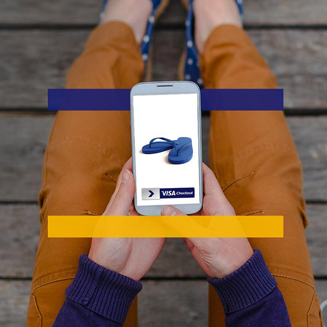 Person looking at a phone in their lap that displays a pair of sandals and the purchasing service Visa Checkout. 