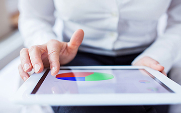 A person interacting with a tablet that is displaying a piechart.