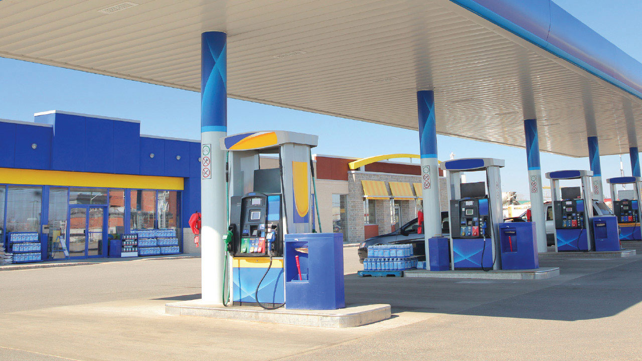 Gas station store front with row of gas pumps in foreground.