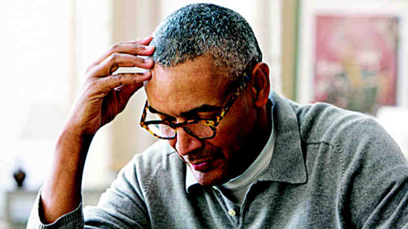 A man is sitting and concentrating while resting his head on his right finger tips.