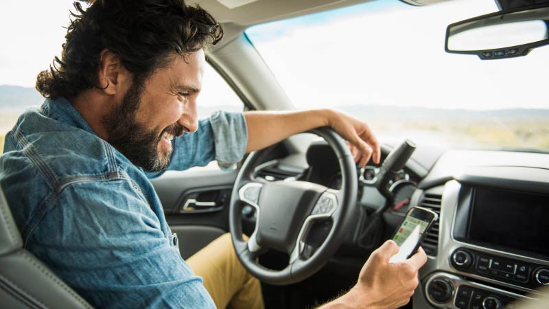 man in car using smart phone