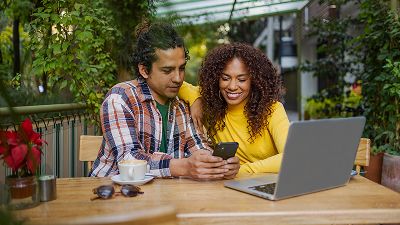 Man and woman using laptop and smartphone in an atrium
