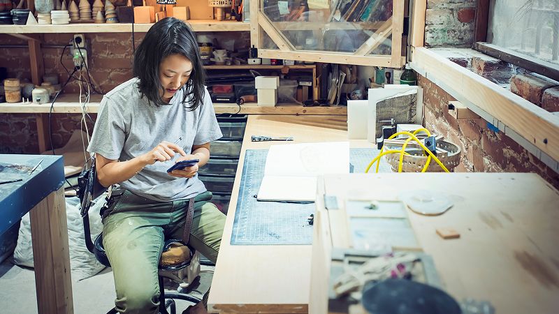 Woman in art studio works on mobile phone