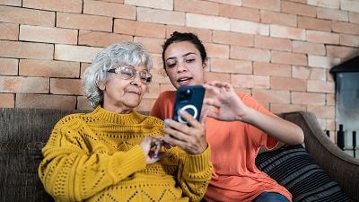 Woman and her granddaughter interact while looking at mobile phone