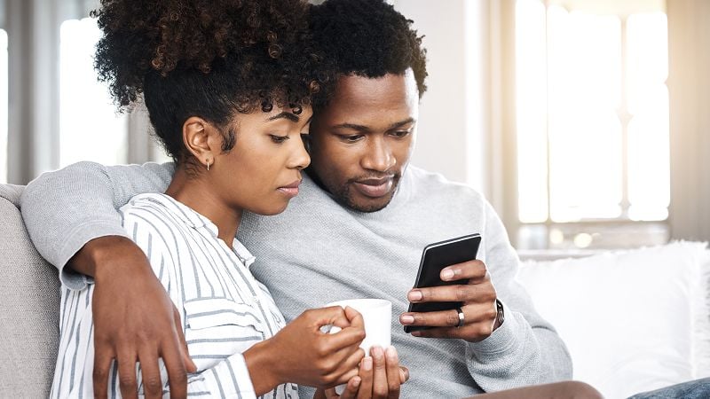  Couple on couch both look at a mobile phone