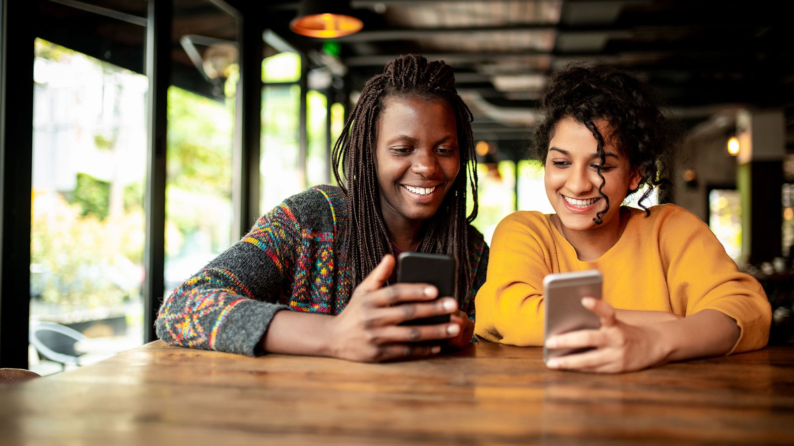 Two friends smile while comparing mobile phone images