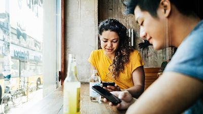 Two people at cafe on their mobile phones