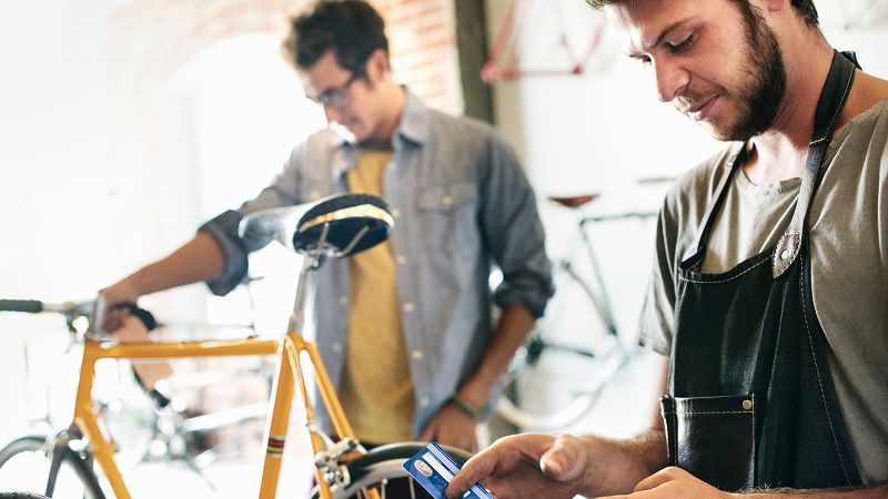 Worker in bicycle shop takes payment from customer